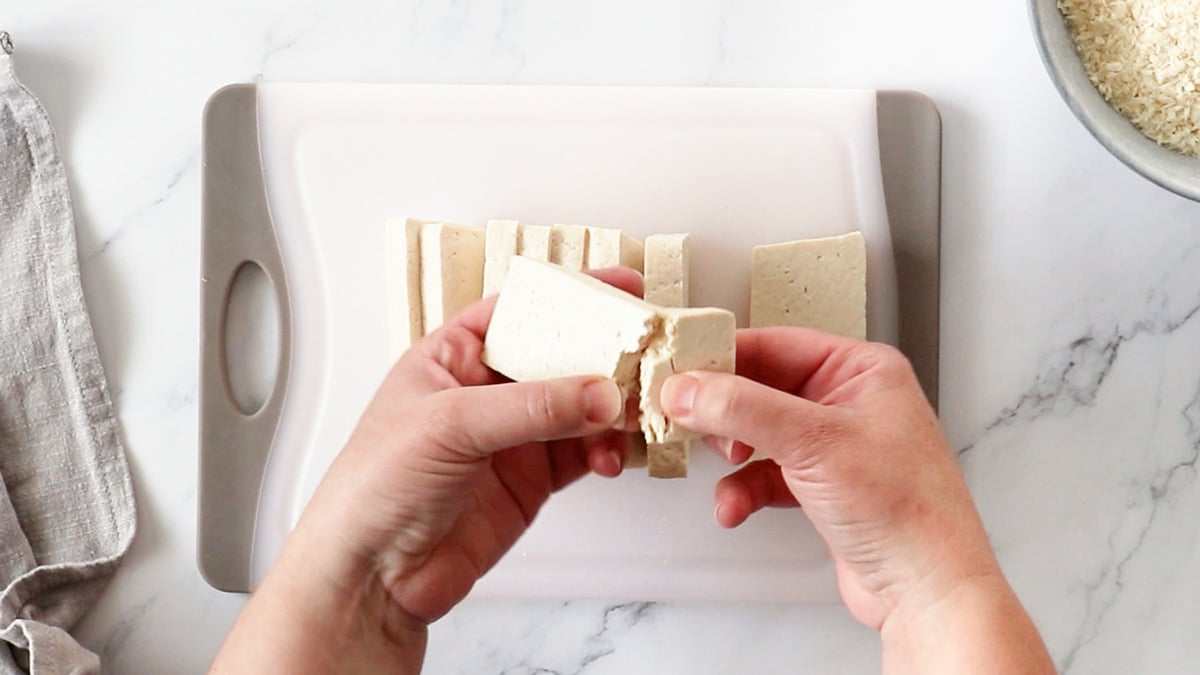 Overhead photo of tofu slabs being torn into nugget-sized pieces.