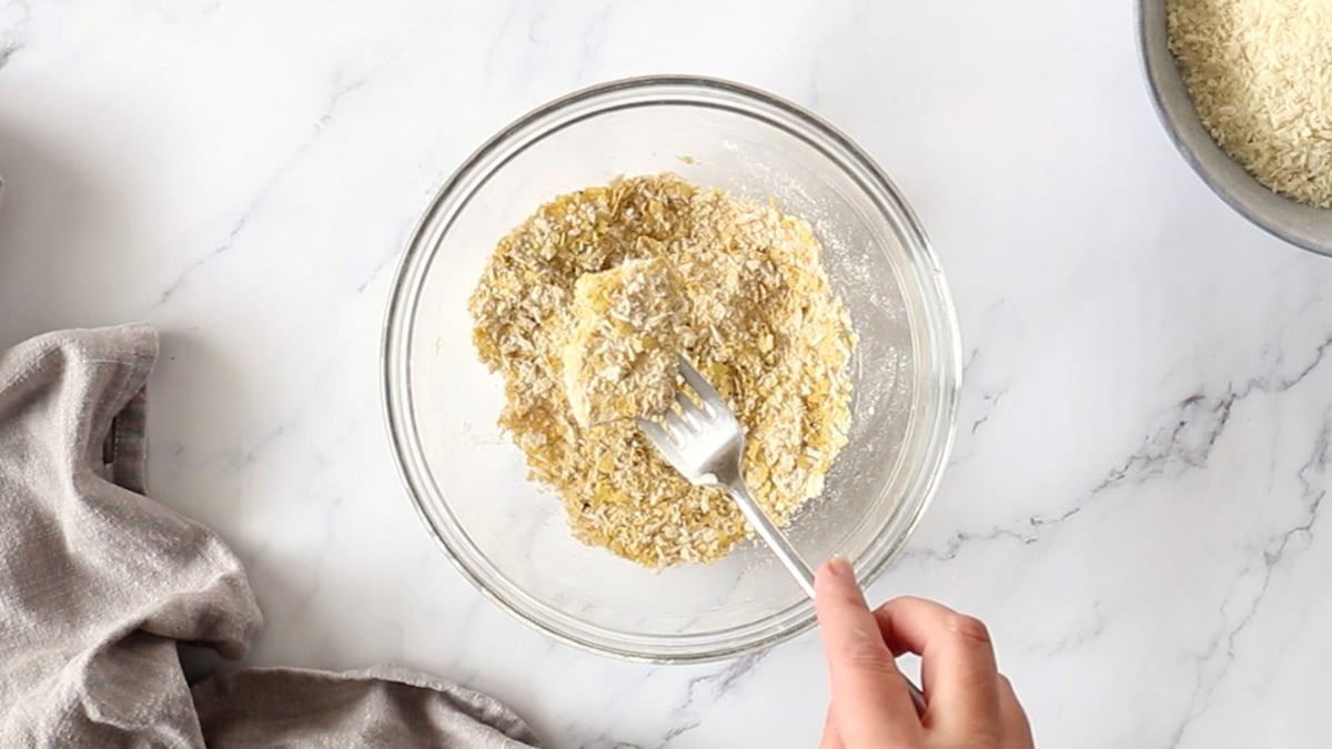 Chunks of tofu being coated in a seasoned panko mixture.