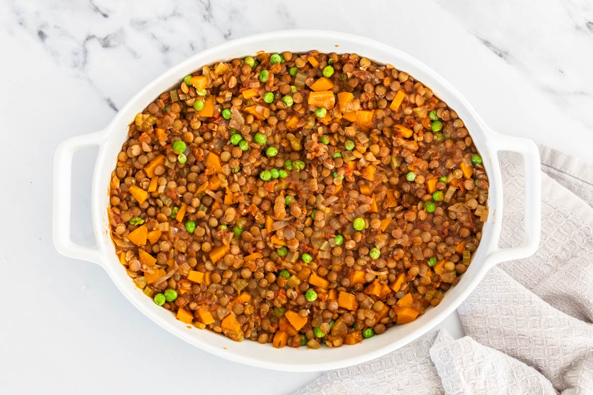 Vegetarian shepherd's pie filling with lentils in a white casserole dish