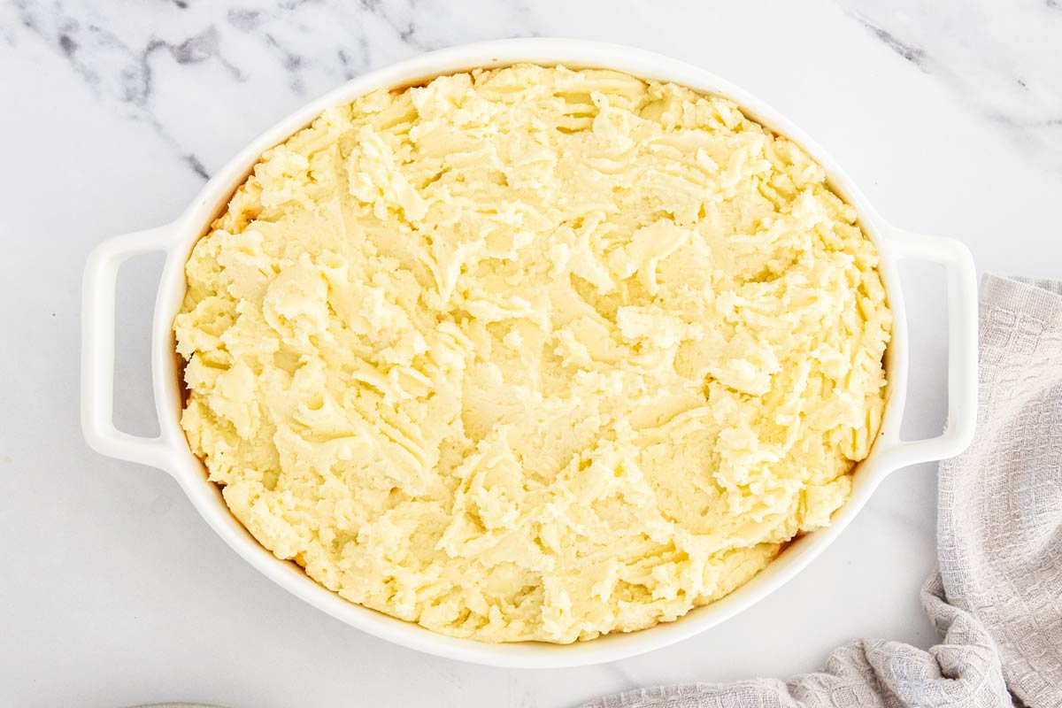 Overhead photo of vegetarian shepherd's pie topped with mashed potatoes in a white casserole dish