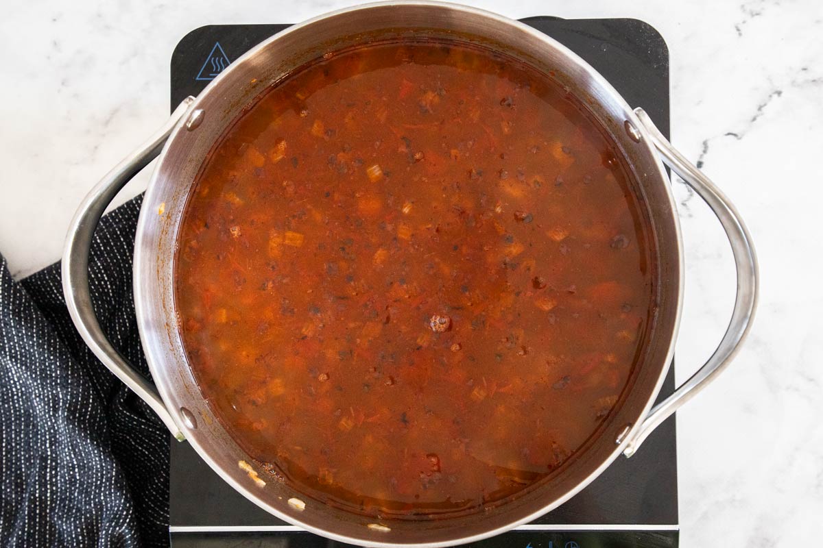 Overhead photo of black bean soup being made in a stainless steel soup pot.