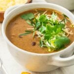 Close up photo of black bean soup in a white bowl with handles