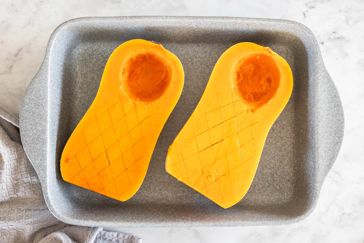 Two butternut squash, halves in a baking pan.