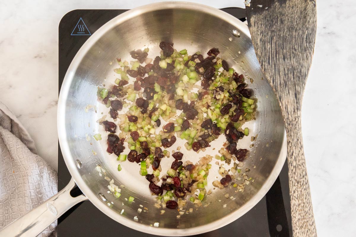 Overhead photo of celery, shallots, and dried cranberries, being sautéed in pan