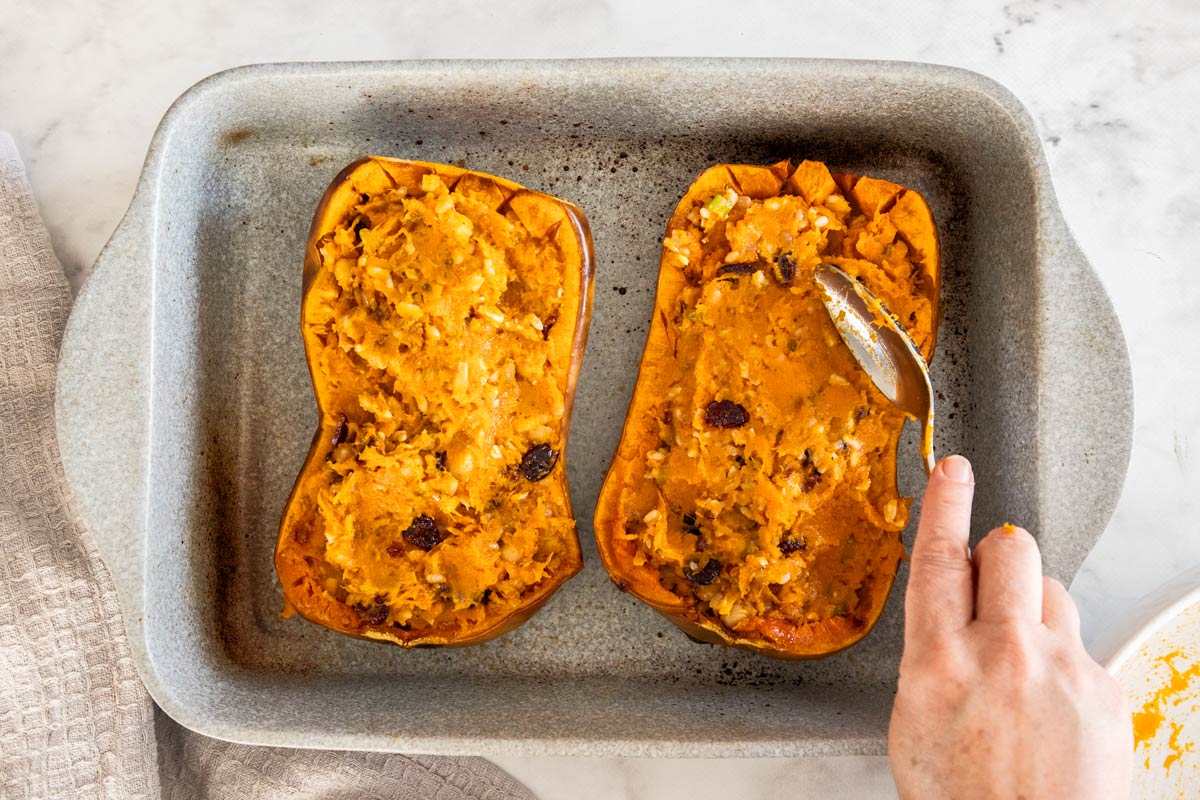 Two butternut squash, halves being stuffed with brown rice stuffing