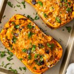 Two stuffed butternut squash halves with brown rice stuffing on a baking sheet.