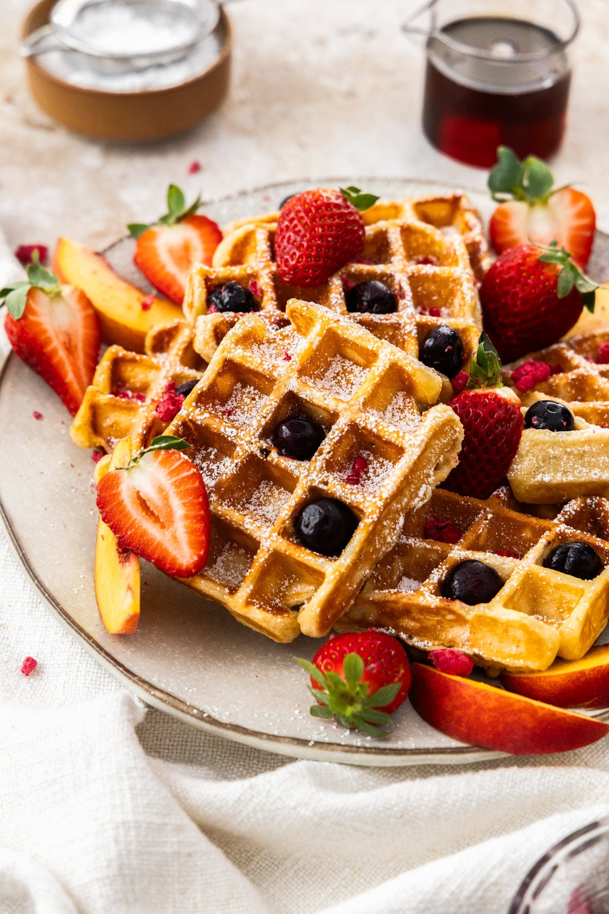 A close up photo of cottage cheese, waffles on a white plate, scattered with berries and fruit.
