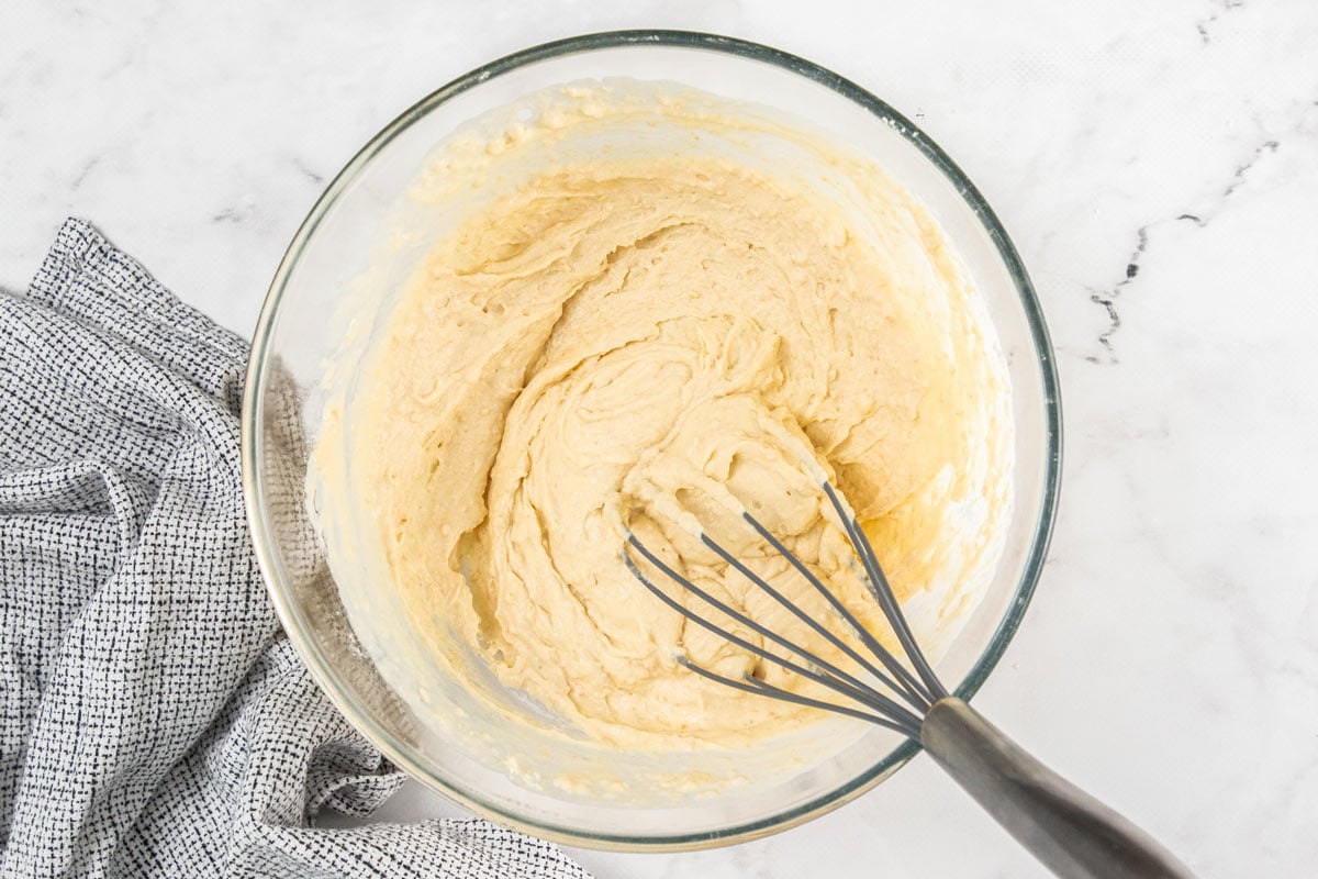 Cottage cheese waffle batter being stirred with a whisk in a glass bowl.