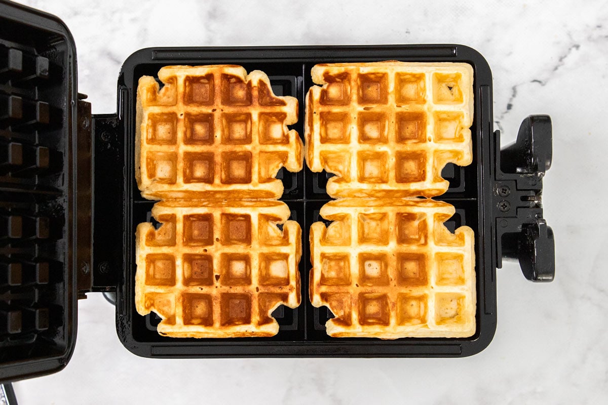 Golden-brown cottage cheese waffles in a waffle iron with four squares.