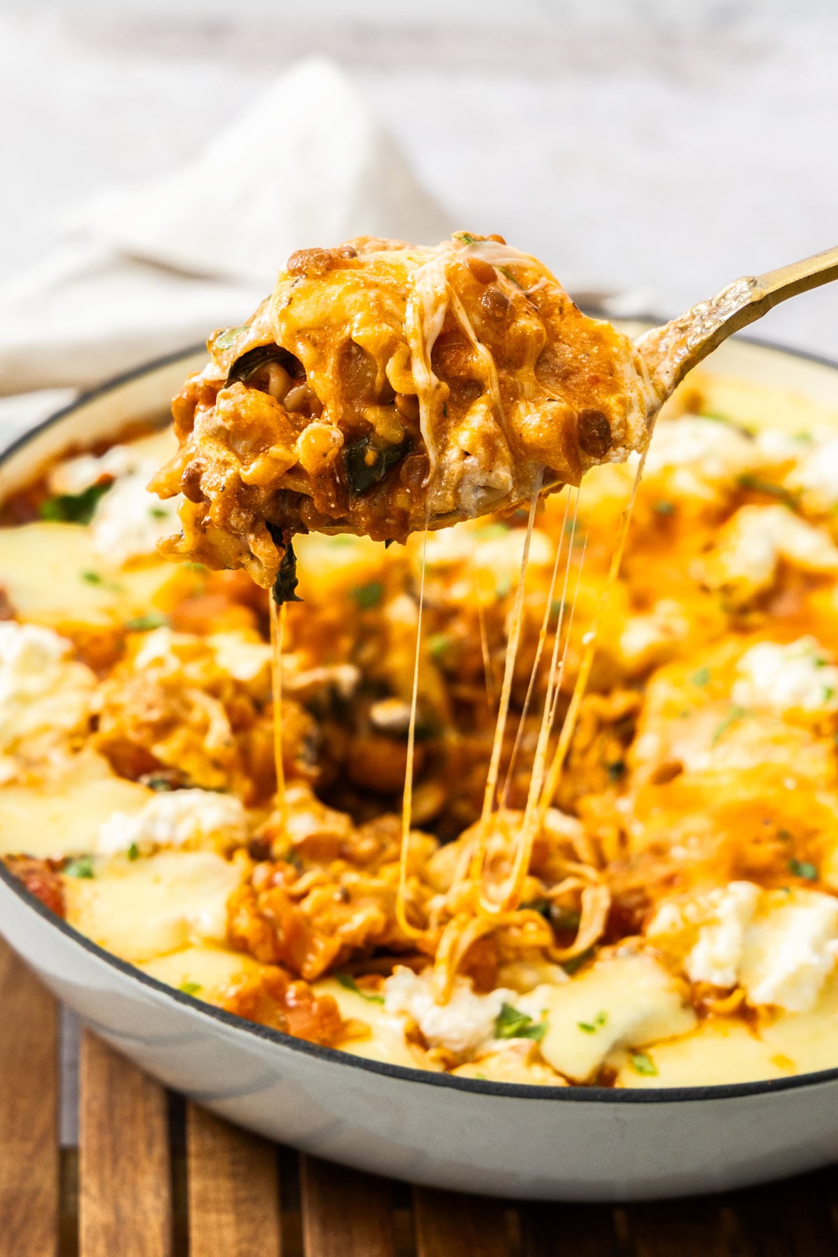 A spoon scooping vegetarian skillet lasagna out of the skillet.