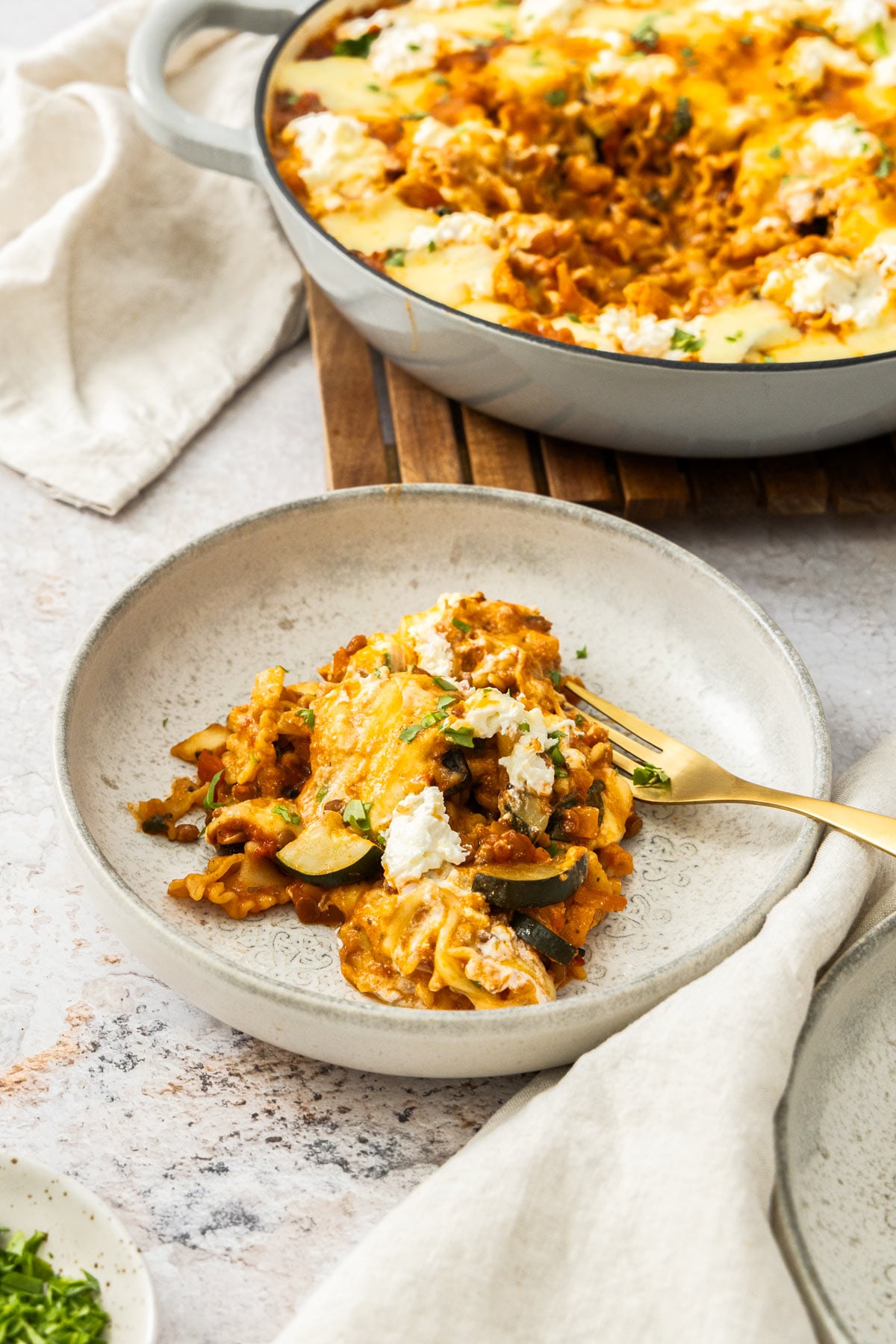 A serving of vegetarian skillet lasagna in a beige bowl with a gold fork to the side.