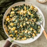 Overhead photo of creamy gnocchi with chickpeas and kale in a white pan.