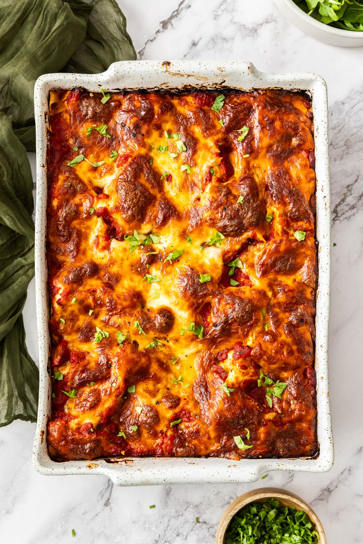 Overhead photo of spinach ricotta lasagna baked in a white lasagna pan.