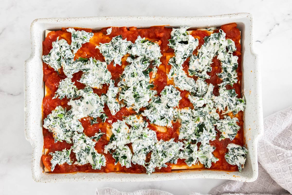 Spinach and ricotta mixture over top of marinara sauce and lasagna noodles.