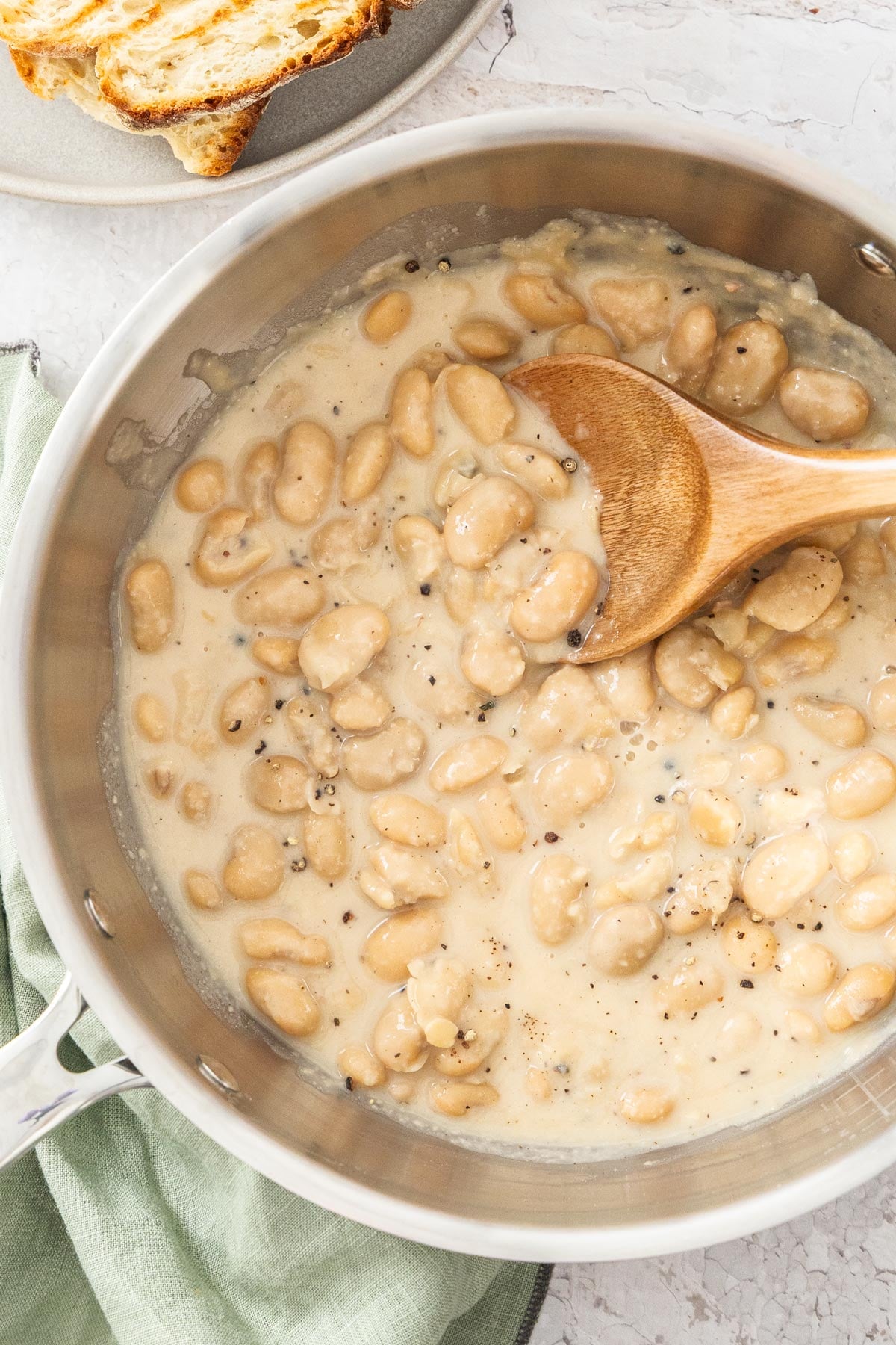 Overhead photo of cacio e pepe beans in a stainless steel skillet