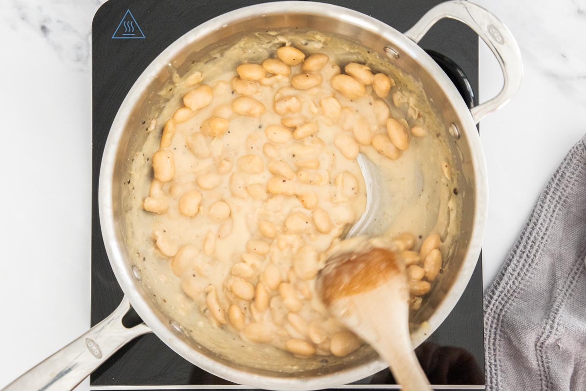 Overhead photo of white beans being cooked with pecorino romano 