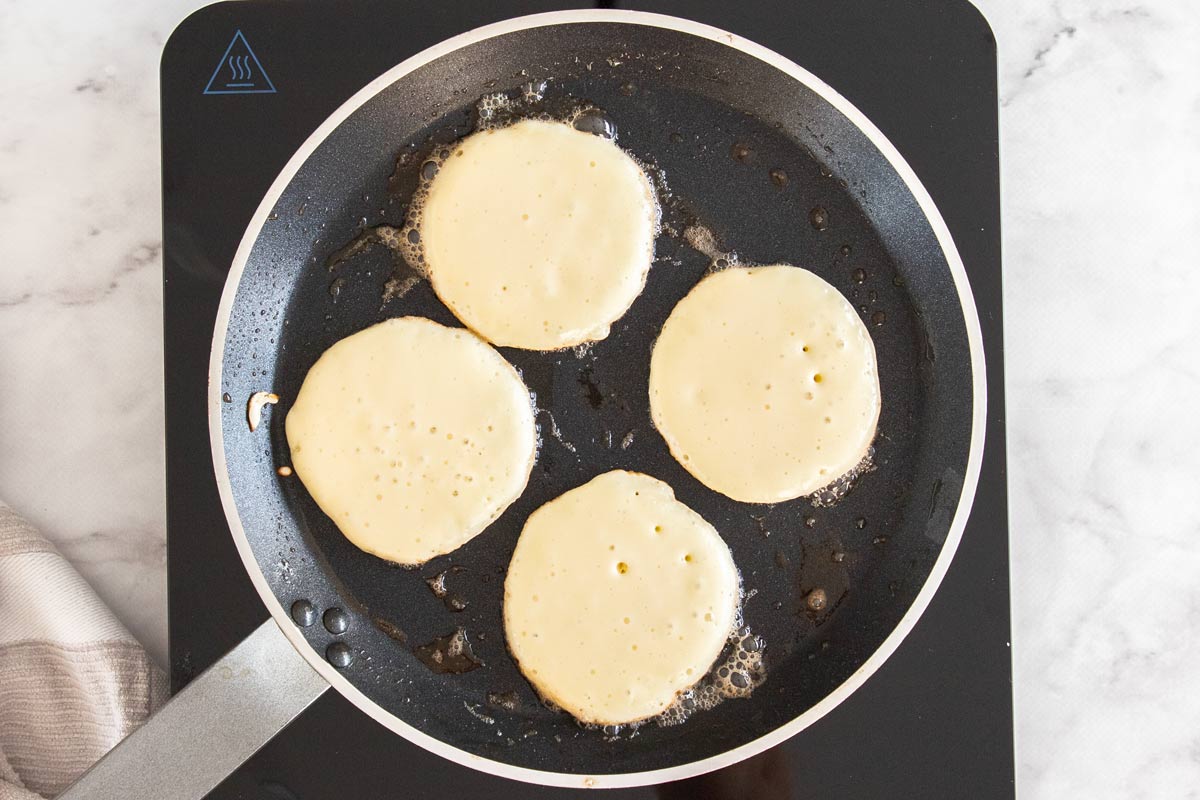 Overhead photo of cottage cheese pancakes cooking in a nonstick pan