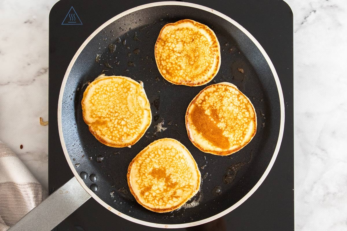 Overhead photo of cottage cheese pancakes cooking in a nonstick pan