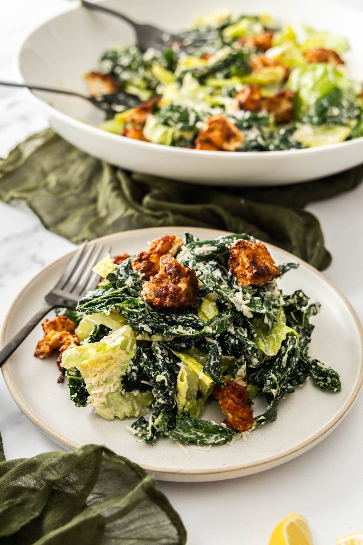 A kale and romaine caesar salad on a white plate