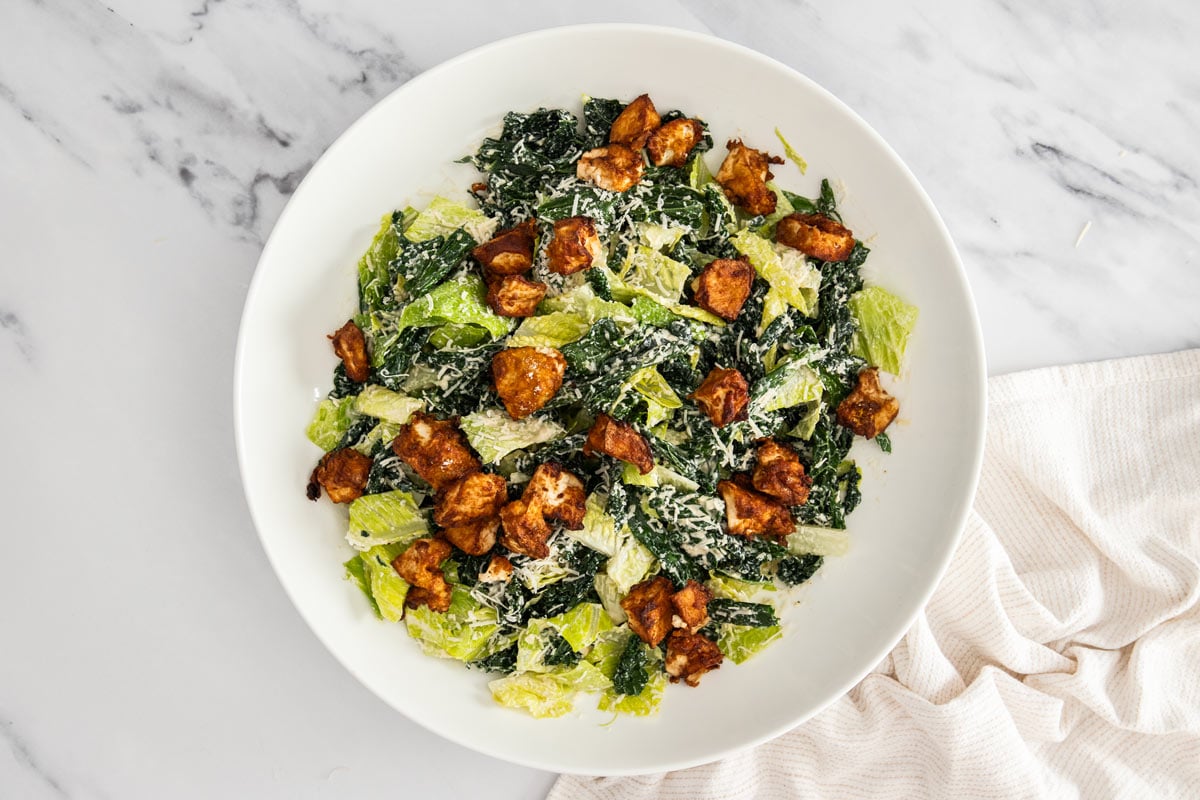 Overhead photo of kale and romaine caesar salad topped with crispy tofu