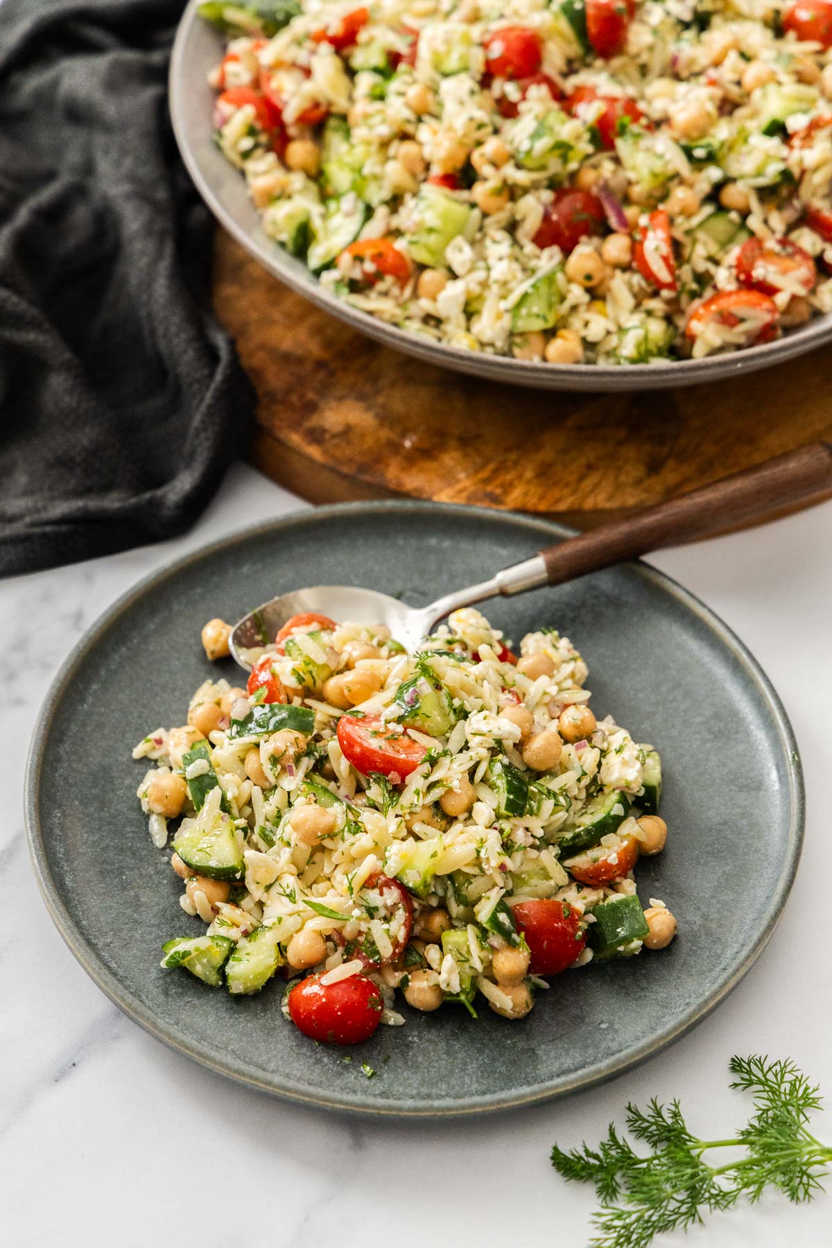 Lemon orzo pasta salad with chickpeas and feta on a grey plate with a fork to the side