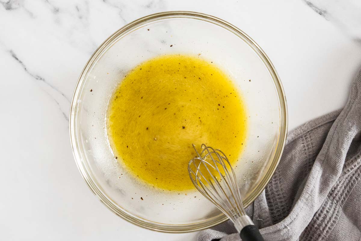 Honey dijon vinaigrette being whisked together in a glass bowl.