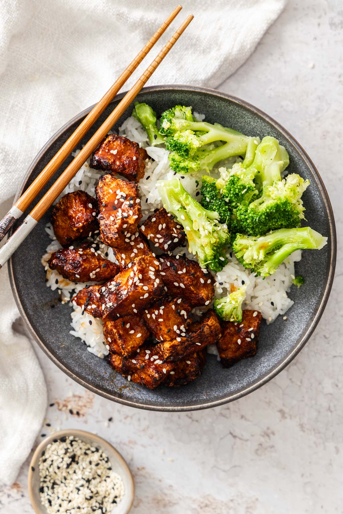 Overhead photo of sticky gochujang tofu in a bowl over rice and broccoli