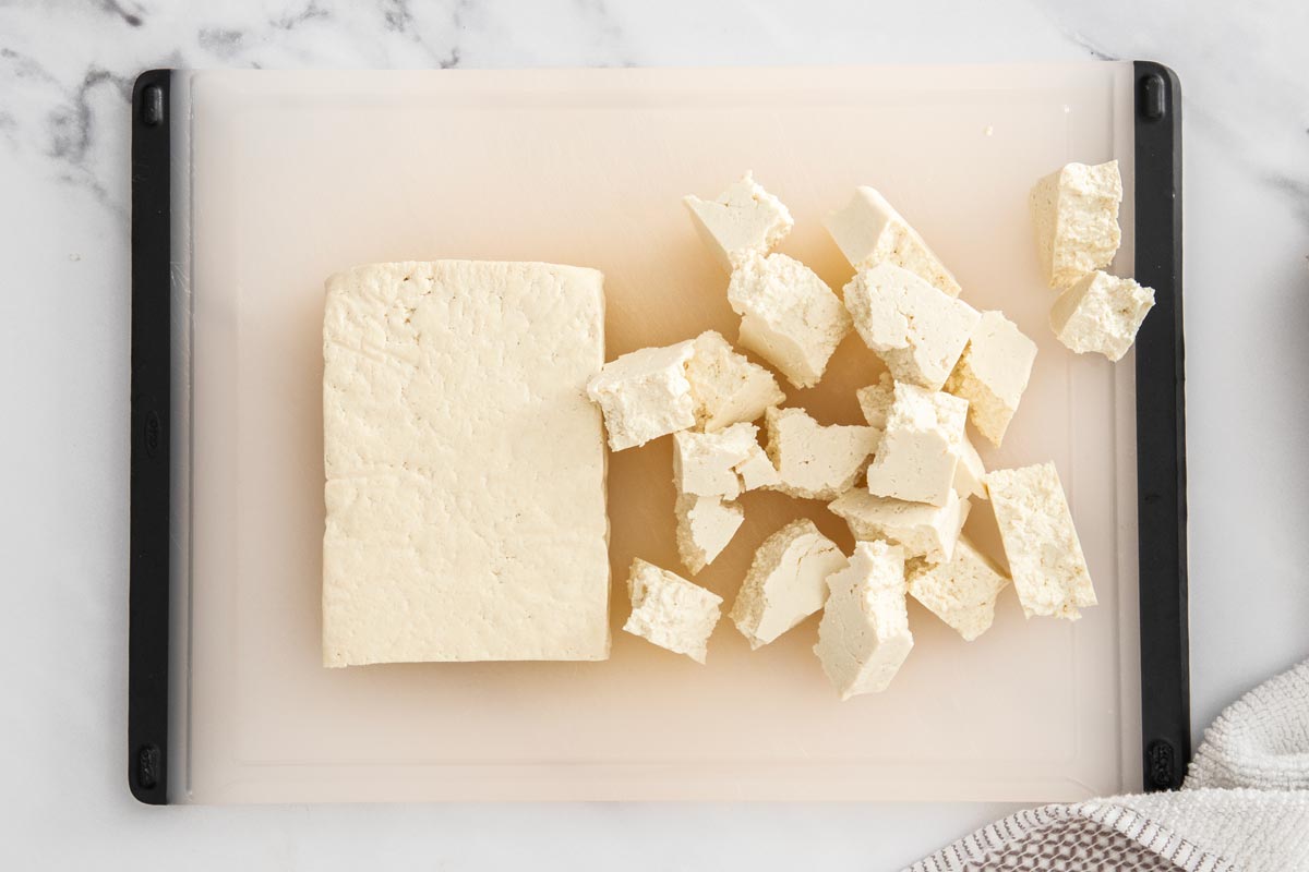 A block of tofu being torn into bite-sized pieces