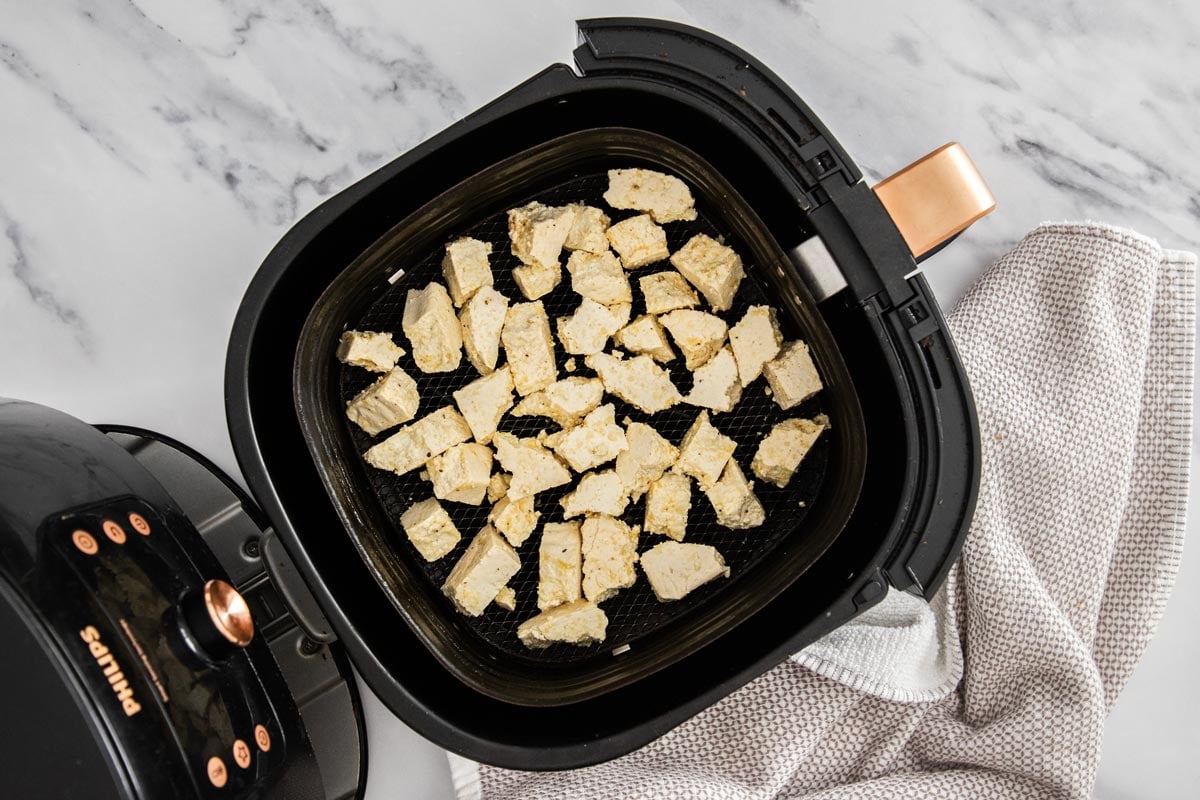 Tofu pieces in the basket of an air fryer