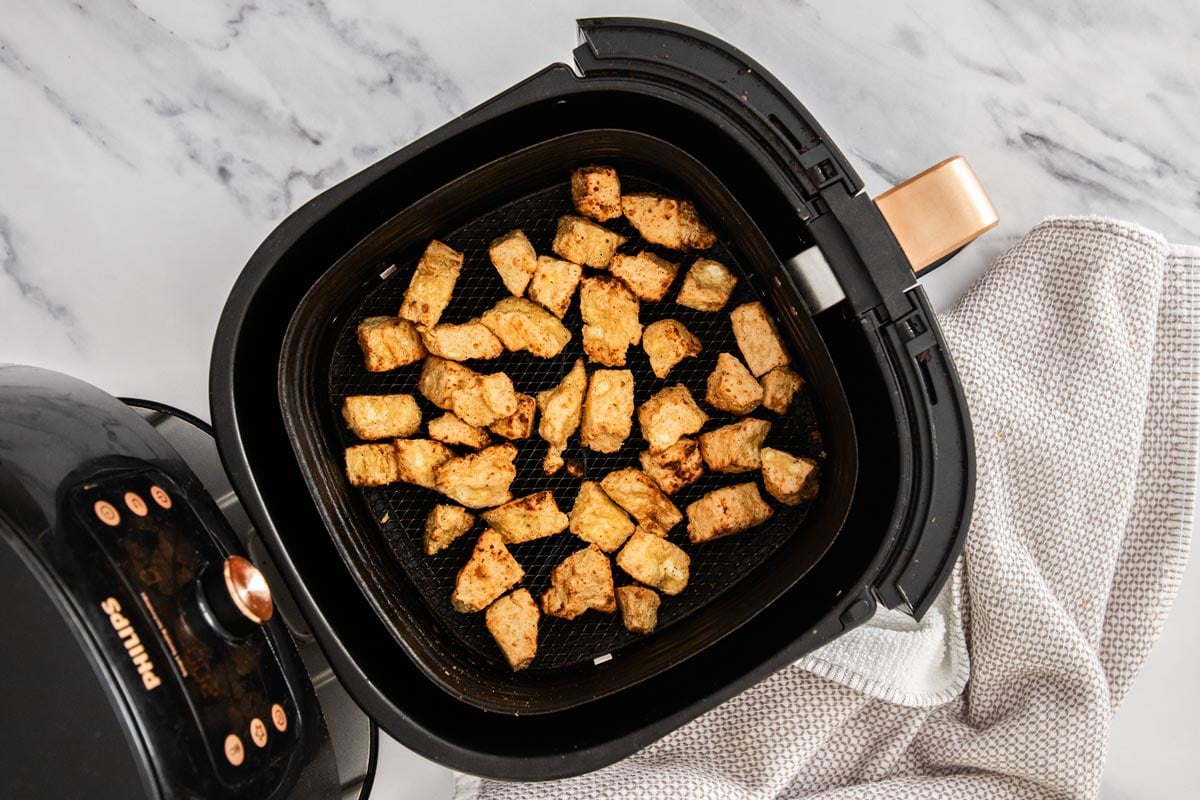 Crispy tofu pieces in the basket of an air fryer