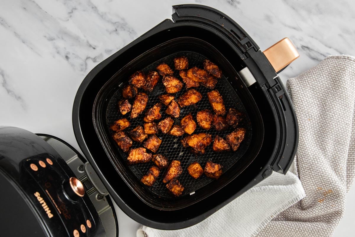 Sticky gochujang tofu pieces in an air fryer basket